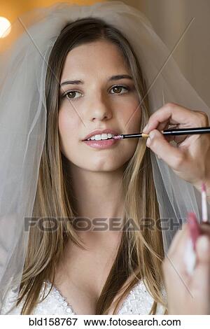 Stock Photo - Caucasian stylist applying makeup on bride. Fotosearch