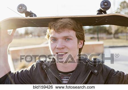 Stock Photograph - Caucasian teenage boy balancing skateboard on head. Fotosearch
