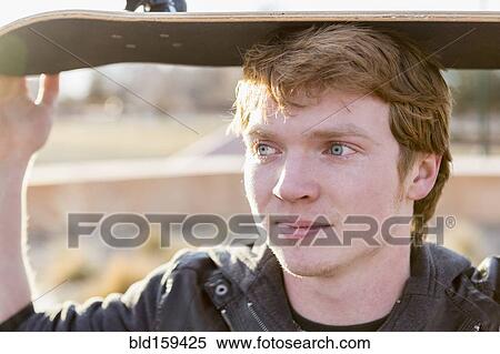 Stock Photography - Caucasian teenage boy holding skateboard outdoors. Fotosearch