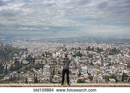 Picture - Caucasian tourist on wall over scenic view of cityscape, Granada, Spain. Fotosearch