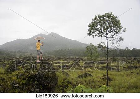 Stock Photograph - Caucasian tourist photographing scenic view of jungle. Fotosearch