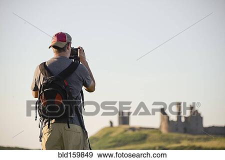 Caucasian tourist photographing Dunstanburgh castle, Northumberland, United Kingdom View Large Photo Image Stock Photo - Caucasian tourist photographing Dunstanburgh castle, Northumberland, United Kingdom. Fotosearch