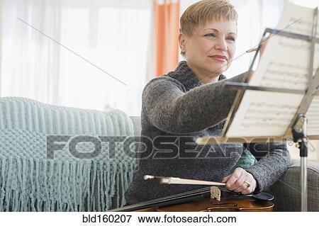 Stock Photo - Caucasian violinist writing on sheet music. Fotosearch