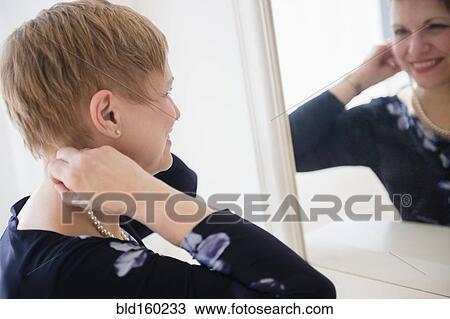 Stock Image - Caucasian woman admiring herself in mirror. Fotosearch