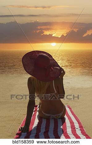 Stock Photo - Caucasian woman admiring sunset on beach. Fotosearch