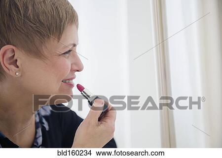 Picture - Caucasian woman applying lipstick. Fotosearch