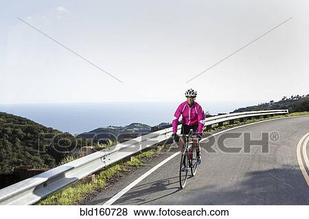 Caucasian woman biking on remote mountain road View Large Photo Image Stock Photo - Caucasian woman biking on remote mountain road. Fotosearch