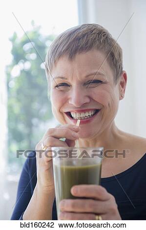 Stock Image - Caucasian woman drinking glass of healthy juice. Fotosearch