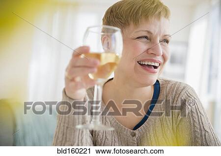 Caucasian woman drinking glass of wine in living room View Large Photo Image Stock Image - Caucasian woman drinking glass of wine in living room. Fotosearch
