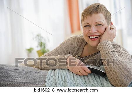 Caucasian woman holding remote control on sofa View Large Photo Image Stock Photo - Caucasian woman holding remote control on sofa. Fotosearch