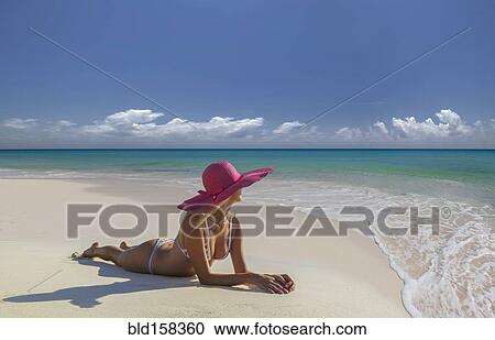 Stock Image - Caucasian woman laying on beach. Fotosearch