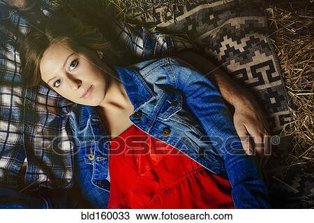 Stock Image - Caucasian woman laying with boyfriend on haystacks. Fotosearch