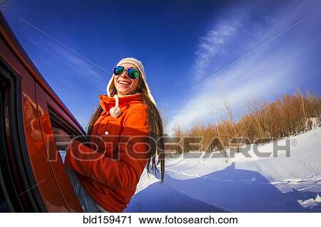 Stock Image - Caucasian woman leaning out car window in snowy field. Fotosearch