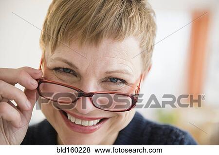 Stock Photo - Caucasian woman peering over eyeglasses. Fotosearch