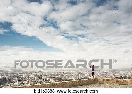 Stock Photo - Caucasian woman photographing scenic view of cityscape, Granada, Spain. Fotosearch