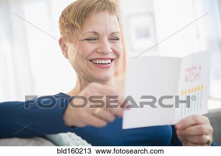 Stock Image - Caucasian woman reading birthday card. Fotosearch