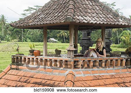 Stock Photo - Caucasian woman reading book on rooftop balcony. Fotosearch