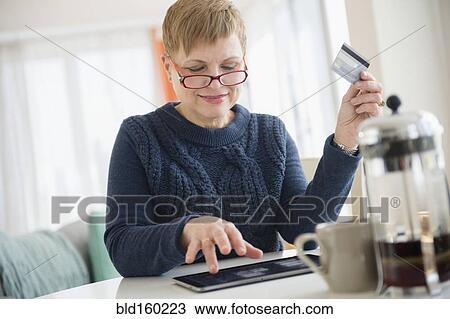 Stock Image - Caucasian woman shopping online on digital tablet. Fotosearch