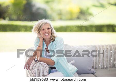 Stock Image - Caucasian woman sitting on sofa outdoors. Fotosearch