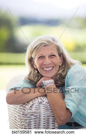 Stock Image - Caucasian woman sitting on sofa outdoors. Fotosearch