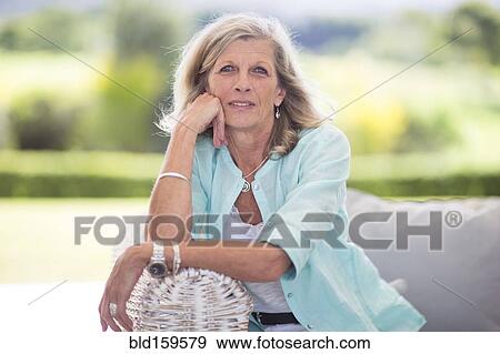 Stock Photo - Caucasian woman sitting on sofa outdoors. Fotosearch
