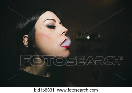 Stock Image - Caucasian woman smoking in nightclub. Fotosearch