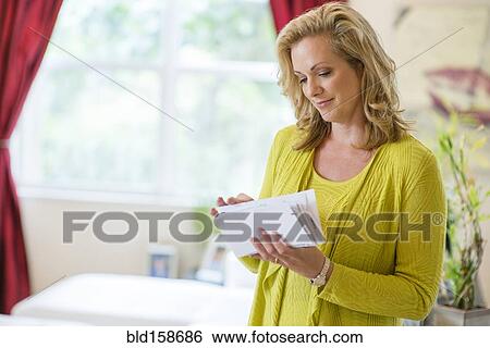 Caucasian woman sorting mail in living room View Large Photo Image Stock Photograph - Caucasian woman sorting mail in living room. Fotosearch
