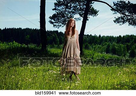 Stock Image - Caucasian woman standing in grass on rural hill. Fotosearch
