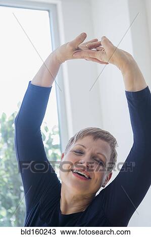 Caucasian woman stretching near window View Large Photo Image Stock Image - Caucasian woman stretching near window. Fotosearch