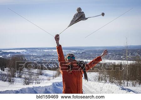 Stock Photo - Caucasian woman swinging hat in snowy rural landscape. Fotosearch