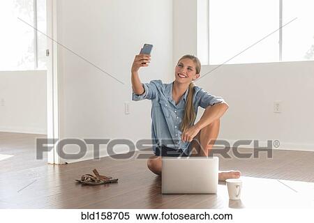 Stock Photography - Caucasian woman taking selfie in empty room. Fotosearch