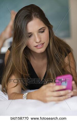 Caucasian woman using cell phone on bed View Large Photo Image Stock Image - Caucasian woman using cell phone on bed. Fotosearch