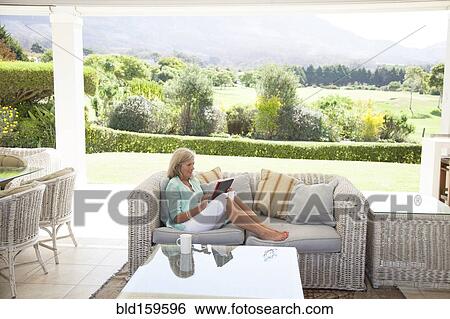 Caucasian woman using digital tablet on sofa View Large Photo Image Stock Photograph - Caucasian woman using digital tablet on sofa. Fotosearch