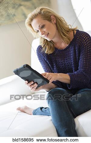 Caucasian woman using digital tablet on sofa View Large Photo Image Stock Photography - Caucasian woman using digital tablet on sofa. Fotosearch