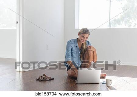 Caucasian woman using laptop in empty room View Large Photo Image Picture - Caucasian woman using laptop in empty room. Fotosearch