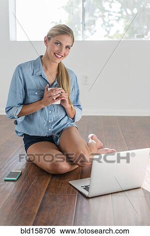 Stock Photograph - Caucasian woman using laptop in empty room. Fotosearch