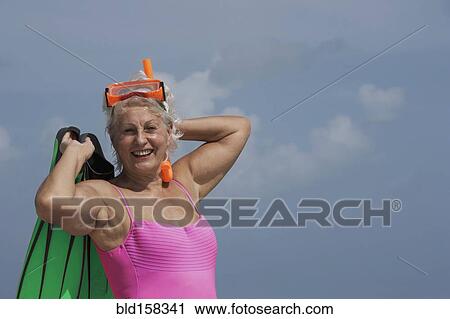 Stock Image - Caucasian woman wearing bathing suit, goggles and fins. Fotosearch