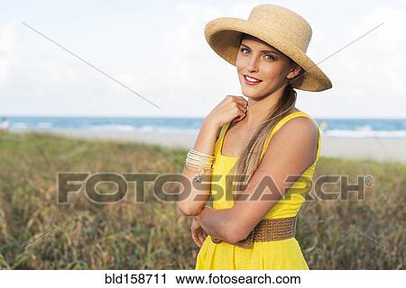 Stock Image - Caucasian woman wearing sun hat near beach. Fotosearch