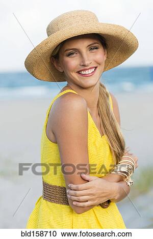 Stock Image - Caucasian woman wearing sun hat on beach. Fotosearch