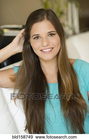 Caucasian woman with long hair sitting on sofa View Large Photo Image Stock Photo - Caucasian woman with long hair sitting on sofa. Fotosearch