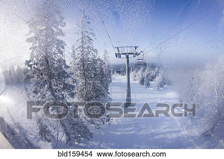 Picture - Chair lift gondolas over snowy slopes. Fotosearch