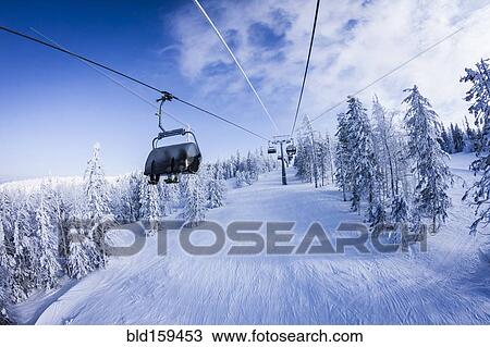 Stock Image - Chair lift gondolas over snowy slopes. Fotosearch