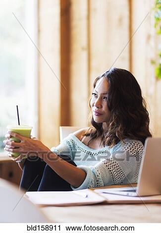 Stock Image - Chinese woman drinking smoothie in cafe. Fotosearch