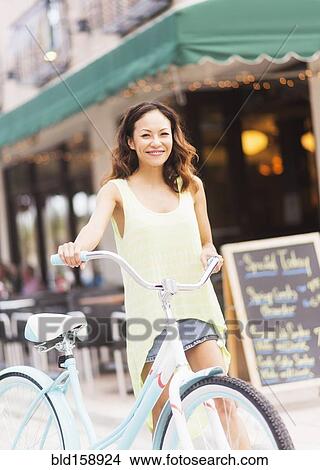 Picture - Chinese woman pushing bicycle on sidewalk. Fotosearch
