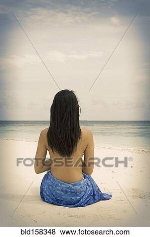 Stock Photo - Chinese woman sitting on tropical beach. Fotosearch