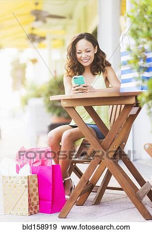 Stock Photo - Chinese woman using cell phone at sidewalk cafe. Fotosearch