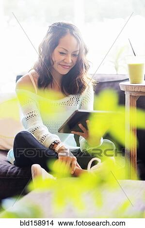 Picture - Chinese woman using digital tablet on sofa. Fotosearch