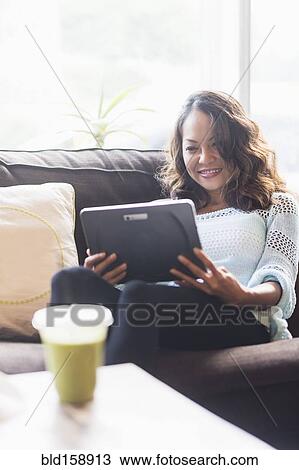 Chinese woman using digital tablet on sofa View Large Photo Image Stock Image - Chinese woman using digital tablet on sofa. Fotosearch