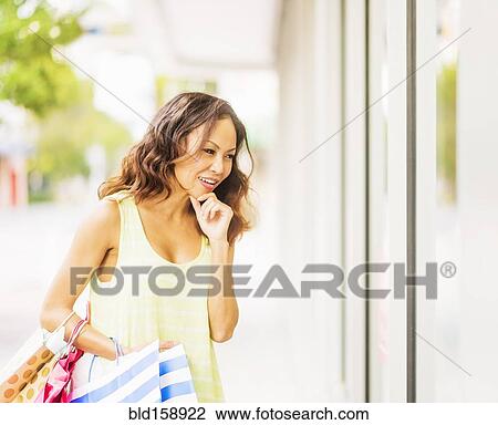 Stock Image - Chinese woman window shopping outside store. Fotosearch