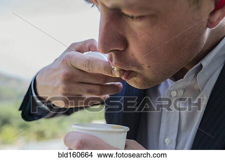 Picture - Close up of Caucasian businessman tasting coffee. Fotosearch